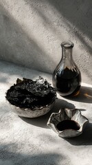 Soy sauce bottle and dried seaweed in ceramic bowls on textured surface