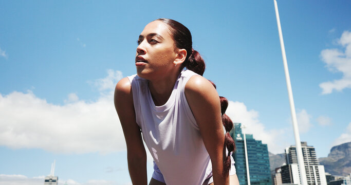 Runner, fitness and woman in city for rest, recovery and break for exercise, workout or training. Sports, low angle and person with fatigue, tired and health in town for marathon, wellness or running - Powered by Adobe