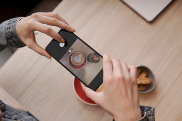 Hands using smartphone taking picture of latte art coffee