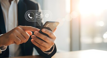 Close-up of a person in a suit using a smartphone with contact icons floating above the screen, illuminated by sunlight.