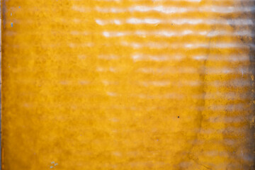 Bright yellow textured surface with wavy patterns caught in natural light during daytime