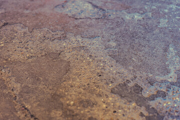 Surface with wet look and colorful reflections creating an abstract pattern in soft lighting