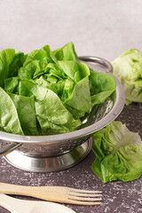 Colander with fresh Boston lettuce on table