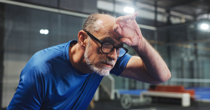 Tennis, tired and mature man with sweat for game, match and training for challenge. Indoor court, sports and senior person breathe with fatigue, rest and break for padel workout, exercise and fitness