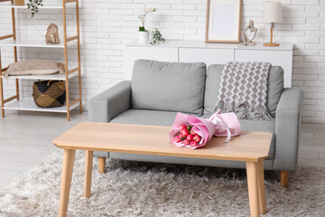 Interior of loft style living room with sofa and table with bouquet of flowers