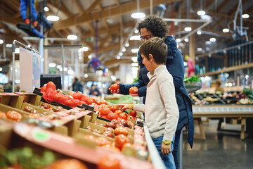Mother and son choosing tomatoes in supermarket