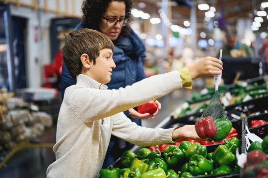 Mother and son buying bell peppers in supermarket