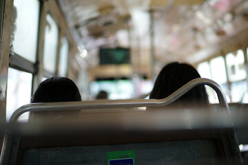 Rear view of two passengers sit inside the traditional public bus in Bangkok