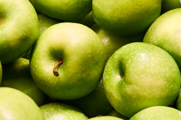 A close-up of fresh, crisp green apples arranged on a clean white background. The vibrant green color and natural texture of the apples make them perfect for healthy lifestyle, nutrition