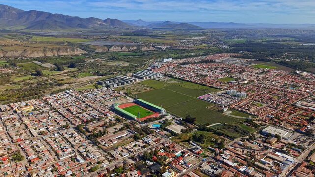 Aerial establishing panoramic view of the city of Ovalle in the Limari Valley on a sunny day with mountains surrounding a city with low-rise condominiums.