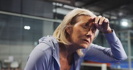 Padel, senior and woman with sweat, tired and rest after game, match and training for challenge. Indoor court, sports and person on break, breathe and fatigue for tennis workout, exercise and fitness