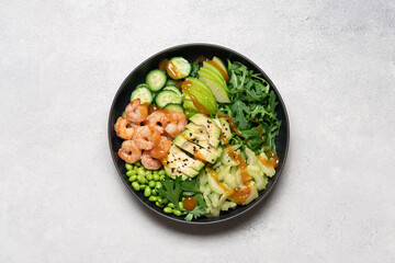 Fresh shrimp and avocado salad with celery, apple, arugula, edamame, cucumber, and parsley on light background, healthy clean eating concept