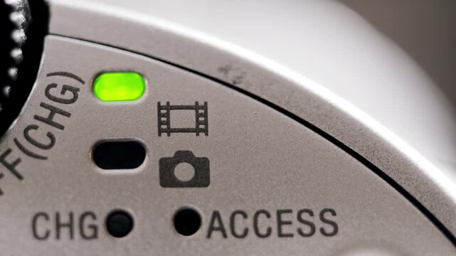 Macro close up of silver camcorder power LED turning on and off with subtle hand movement