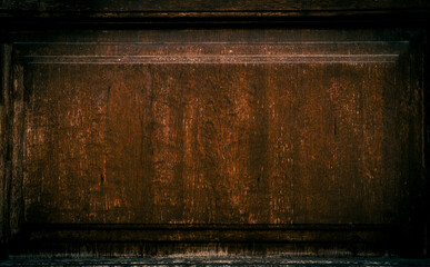 An old dark wooden door with a rectangular plate in the center, but it is currently empty and weathered.