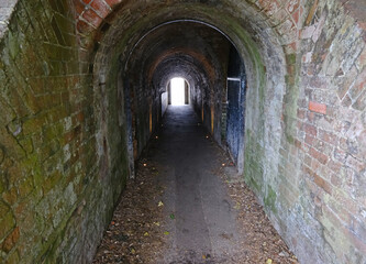 Obraz premium Long Brick Archway Tunnel Leading to Light, Part of Historic Fortifications in Portsmouth, England