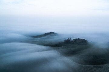 Aerial view of a landscape shrouded in ethereal mist, the rolling Wittenham Clumps peeking through the fog like islands in a sea of white, Oxfordshire, England, United Kingdom.