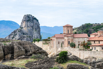 A historic monastery with a domed church nestles atop rocky cliffs in Meteora,