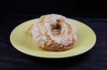 Two ring shaped cupcakes on a yellow plate on a black background.