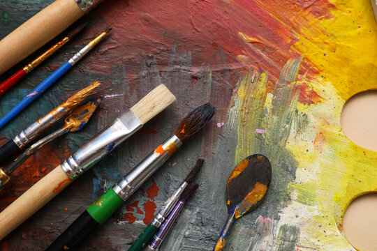 Artist brushes and knives on palette with paints, closeup - Powered by Adobe