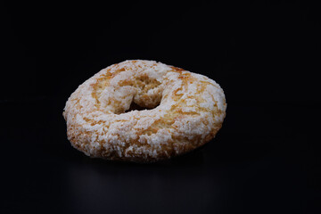 Ring shaped cupcake with sugar sprinkles and cupcake pieces on black background.