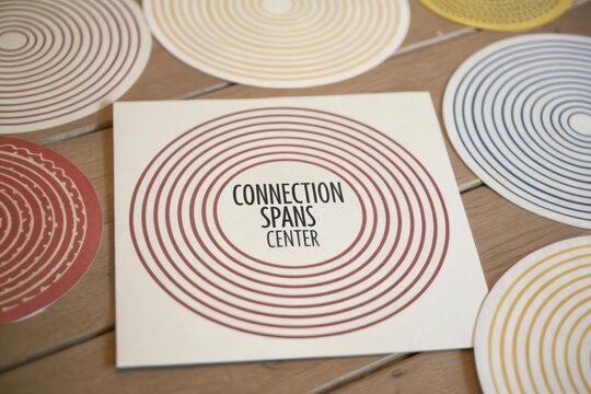 Flat lay view of a modern card featuring concentric red circles and Connection Spans Center text
