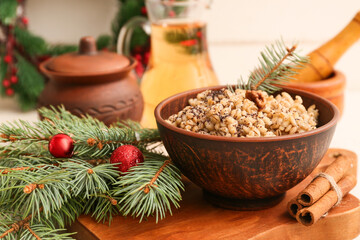 Bowl of traditional Ukrainian Kutya dish with cinnamon and Christmas tree branches on white table