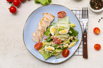 Plate of tasty chicken Caesar salad with tomatoes and bowl of peppercorn on white background