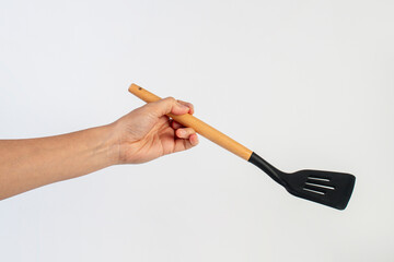 Hand holding kitchen utensils on white background