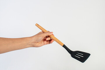 Hand holding kitchen utensils on white background