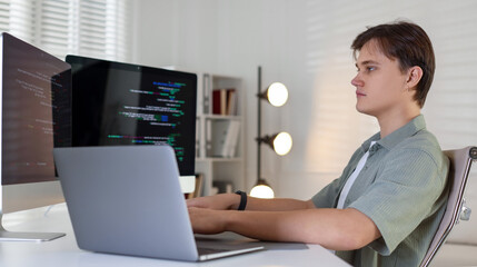 Programmer working on computer and laptop at white table in office