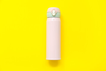 Modern pink thermos on yellow background