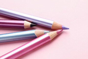 Fototapeta premium Bright eye pencils on pink background, closeup. Space for text
