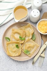 Delicious ravioli with basil served on light grey table, flat lay
