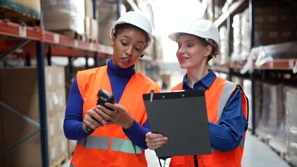 Two female warehouse workers checking inventory with barcode scanner - Powered by Adobe
