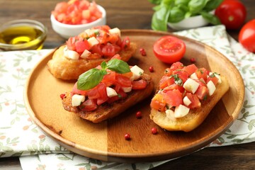 Tasty bruschettas with tomatoes and basil served on wooden table, closeup
