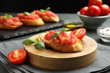 Tasty bruschettas with tomatoes and basil served on black table, closeup