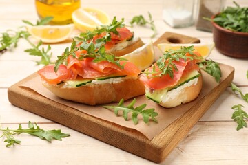 Tasty bruschettas with salmon and cream cheese served on wooden table, closeup
