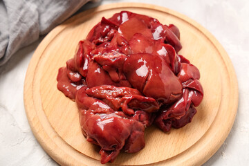 Wooden board with raw liver on light background