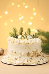 Delicious cake with Christmas decor on beige background against blurred lights, closeup. Bokeh effect