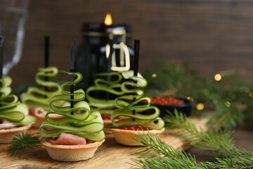 Christmas trees made with cucumber, red caviar, ham and festive decor on table, closeup
