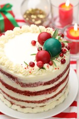 Delicious sponge cake with Christmas decor and burning candles on light table, closeup