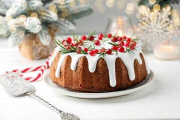 Tasty Christmas cake with icing, cranberries and rosemary on white wooden table, closeup