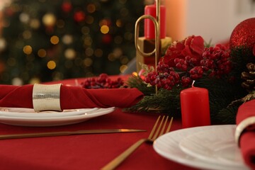 Stylish Christmas table setting with plates, napkins and festive decor indoors, closeup