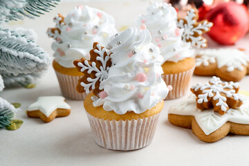 Tasty cupcakes with Christmas decor and gingerbread cookies on white table, closeup