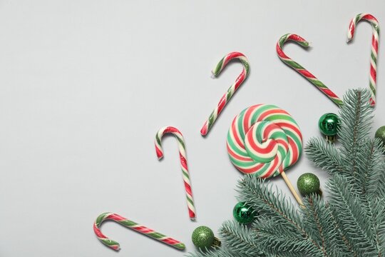 Christmas composition with candy canes, lollipop and decor on white background, flat lay. Space for text