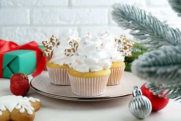 Tasty cupcakes with Christmas decor and gingerbread cookies on white table, closeup