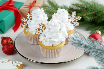 Tasty cupcakes with Christmas decor and gingerbread cookies on white table, closeup