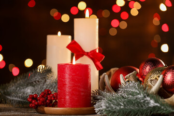 Burning candles and Christmas decor on wooden table against dark background with blurred lights, closeup. Bokeh effect
