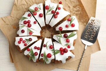 Tasty Christmas cake with cranberries and server on light wooden table, top view