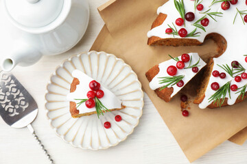 Tasty Christmas cake with cranberries, server and teapot on light wooden table, flat lay